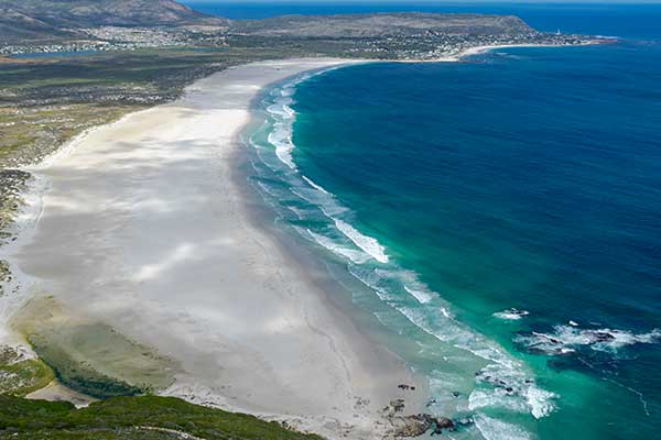 Long empty stretch of Noordhoek Beach near Cape Town with mountains in the distance
