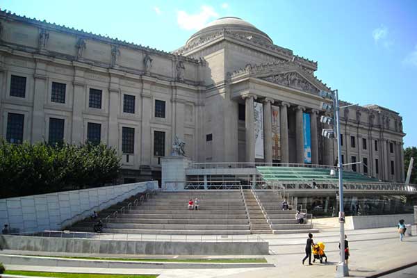 Brooklyn Museum exterior in New York City surrounded by trees and visitors